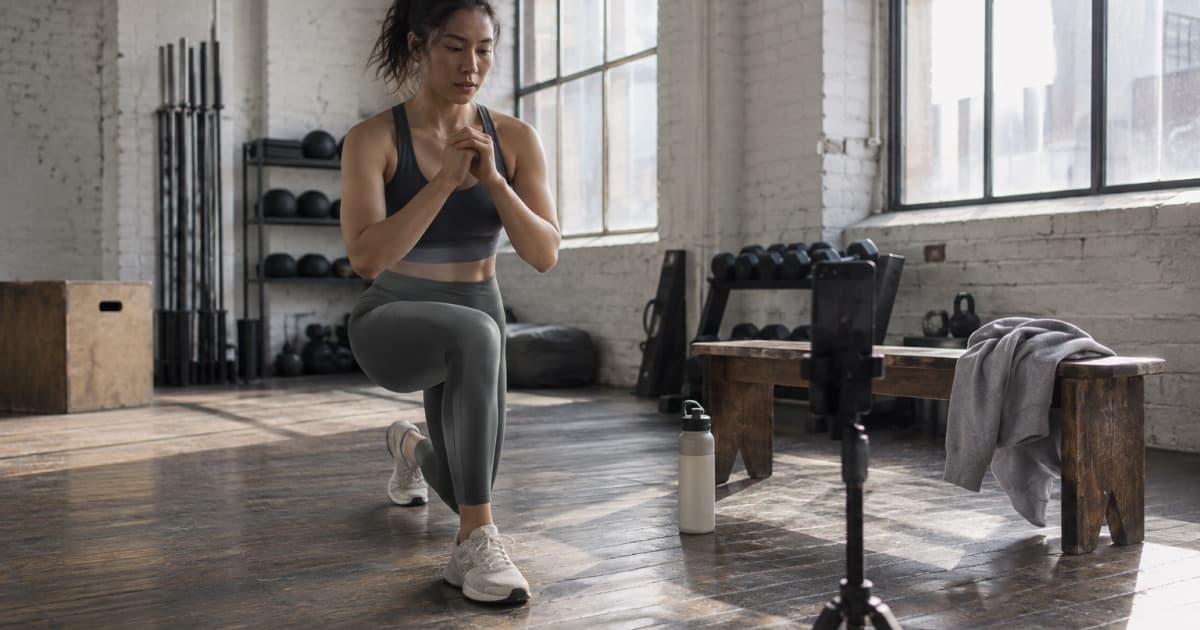 Une coach se filme pendant un exercice avec son téléphone sur un trépied