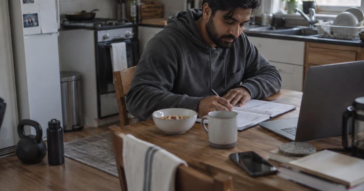 Un coach organise sa semaine dans un agenda papier, une kettlebell à ses pieds